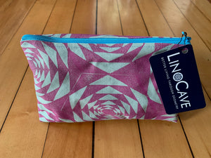 A light green and magenta zipper pouch with a turquoise zipper. Hand block printed with a geometric pattern.