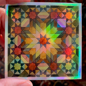 A photograph of a 3" holographic sticker which has a "Moroccan Rosettes" pattern on it in a blend of colors and neutrals.