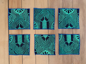 A set of six denim coaters hand block printed in a green geometric design with a blue rolled edge hem.