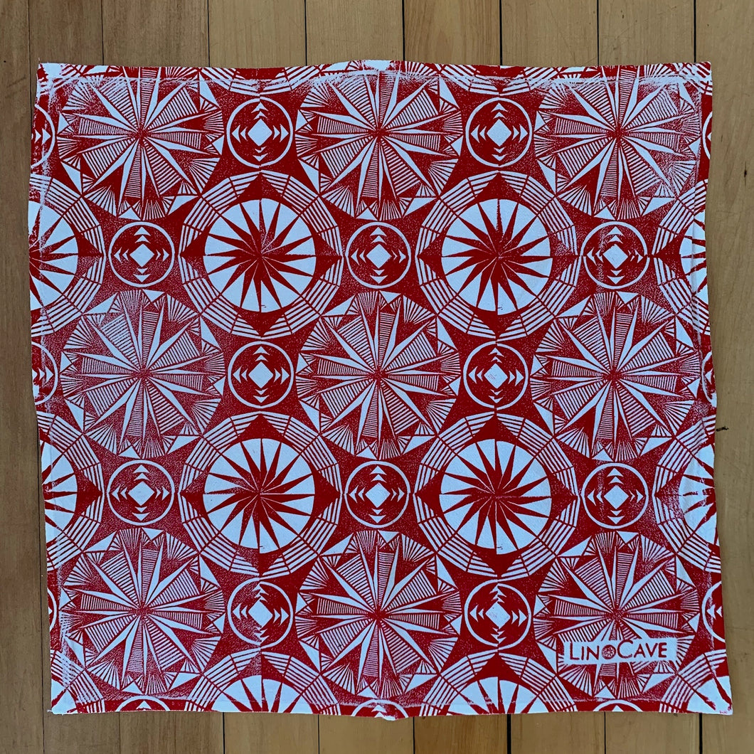 A hand block printed white flour sack towel with red in a geometric pattern. 