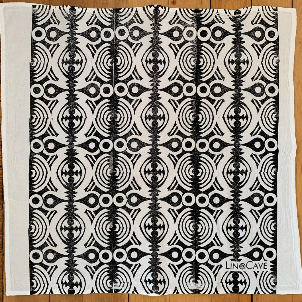 A hand block printed white flour sack towel in a black geometric pattern.  