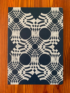 A navy Moleskine sketchbook hand block printed in a white geometric pattern.