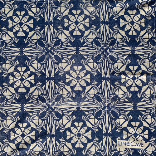 A hand block printed white flour sack towel in blue in a geometric pattern.  