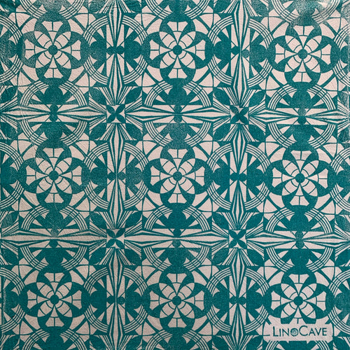 A hand block printed white flour sack towel in turquoise in a geometric pattern.  